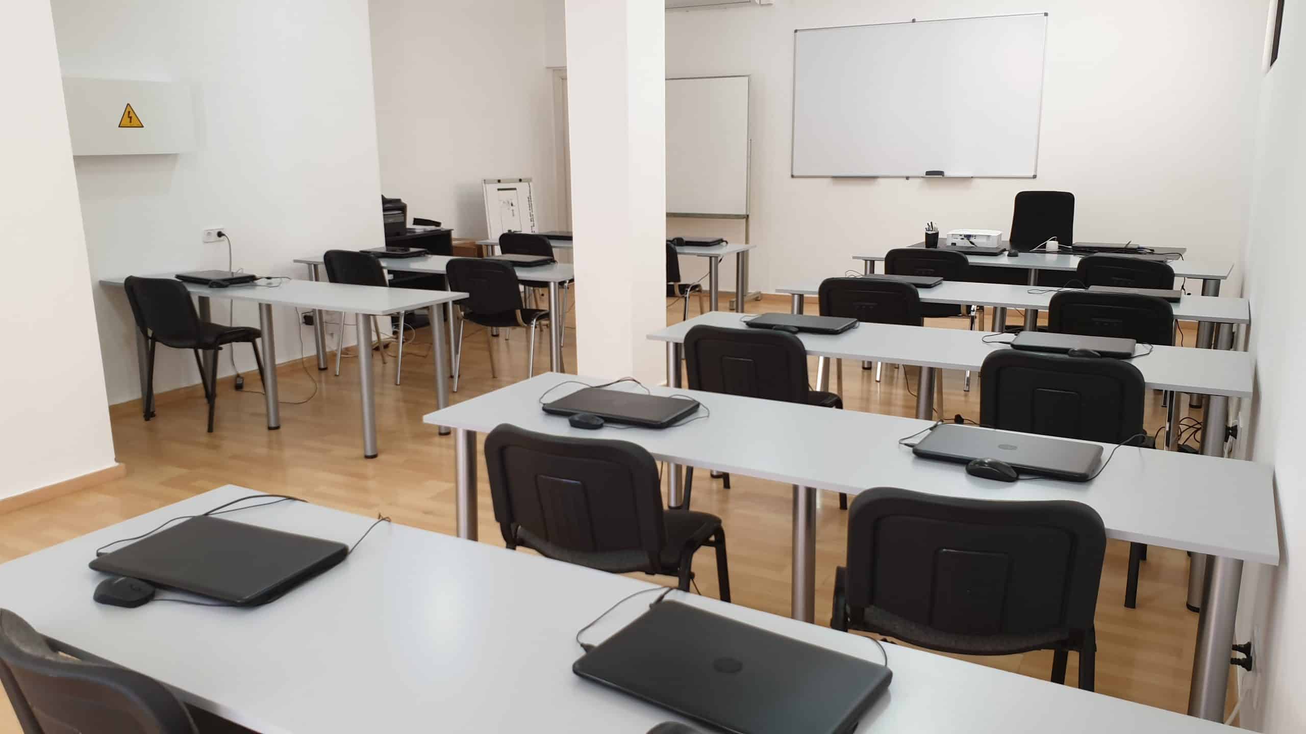 Una aula plena d'ordinadors portàtils i pissarres.