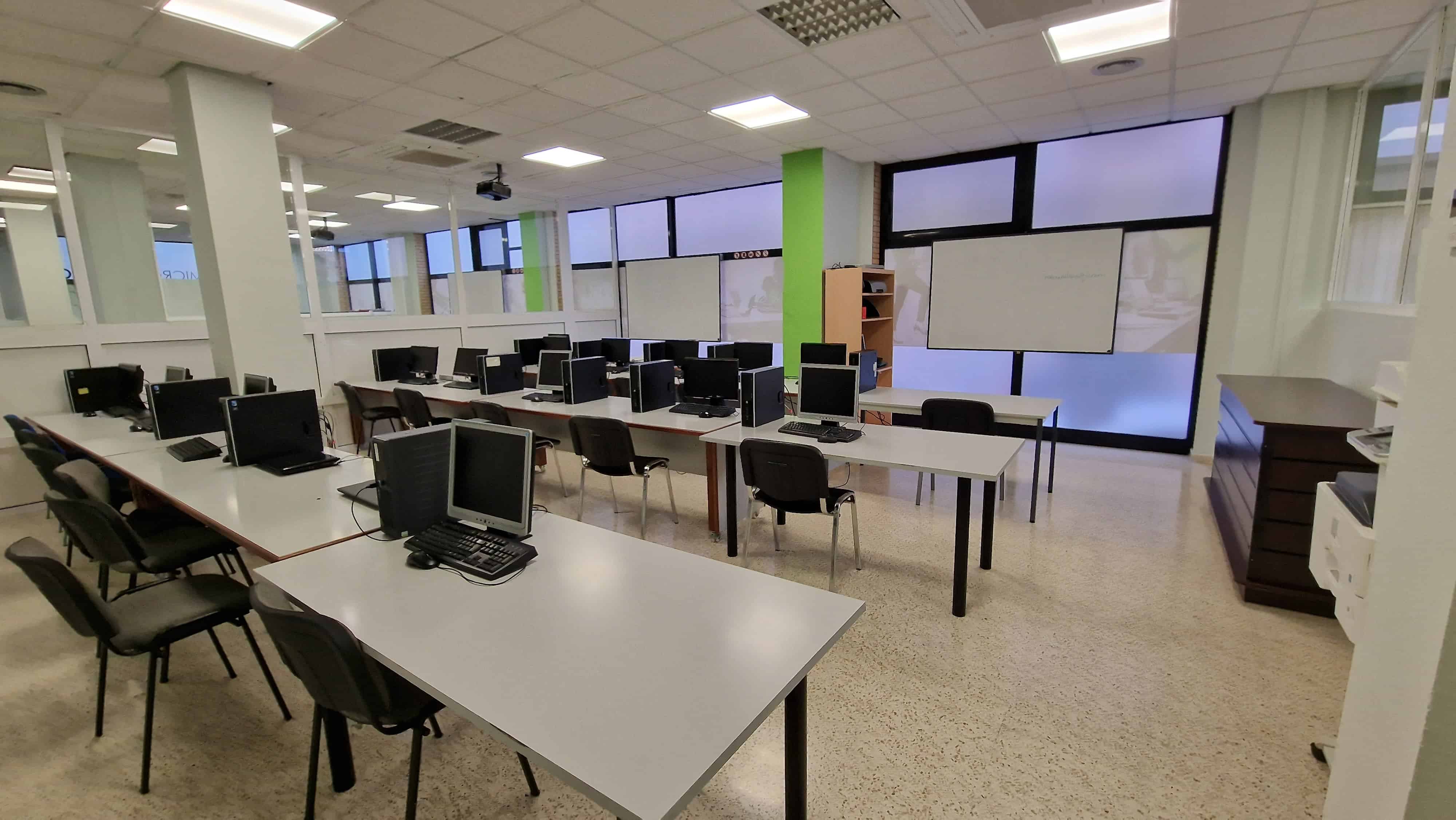 Una aula plena d'ordinadors i pupitres.