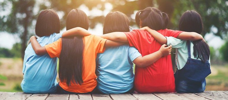 Un grup de noies asiàtiques assegudes en un banc i abraçant-se.