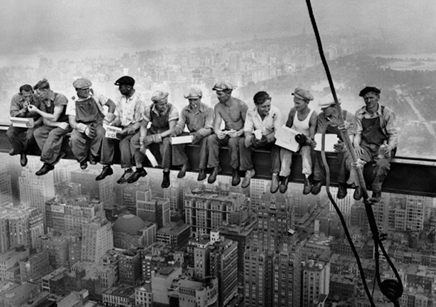 Un grup de treballadors de la construcció asseguts a la vora d'un edifici.