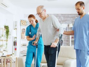 Un home amb crosses està sent ajudat per una infermera en una sala d